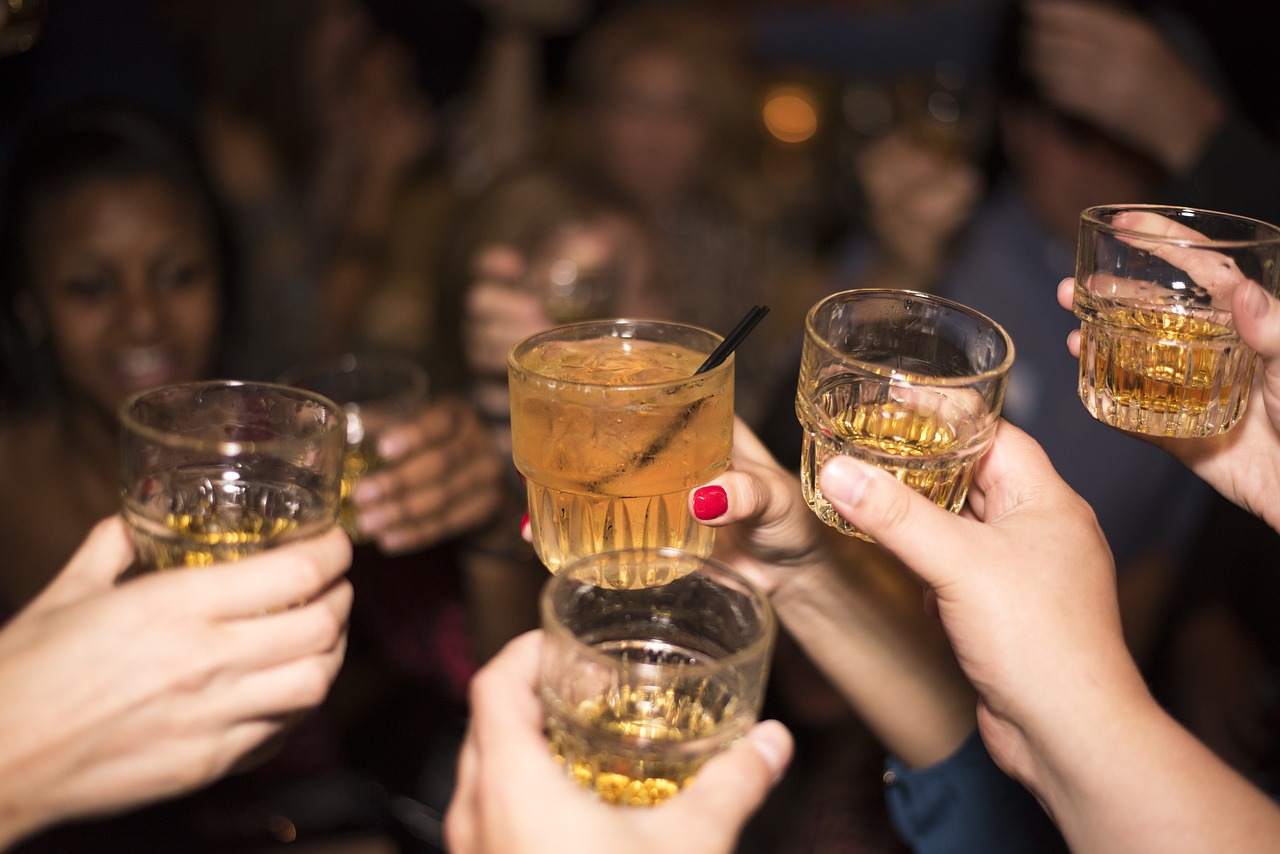 group of people clinking glasses of amber liquid together