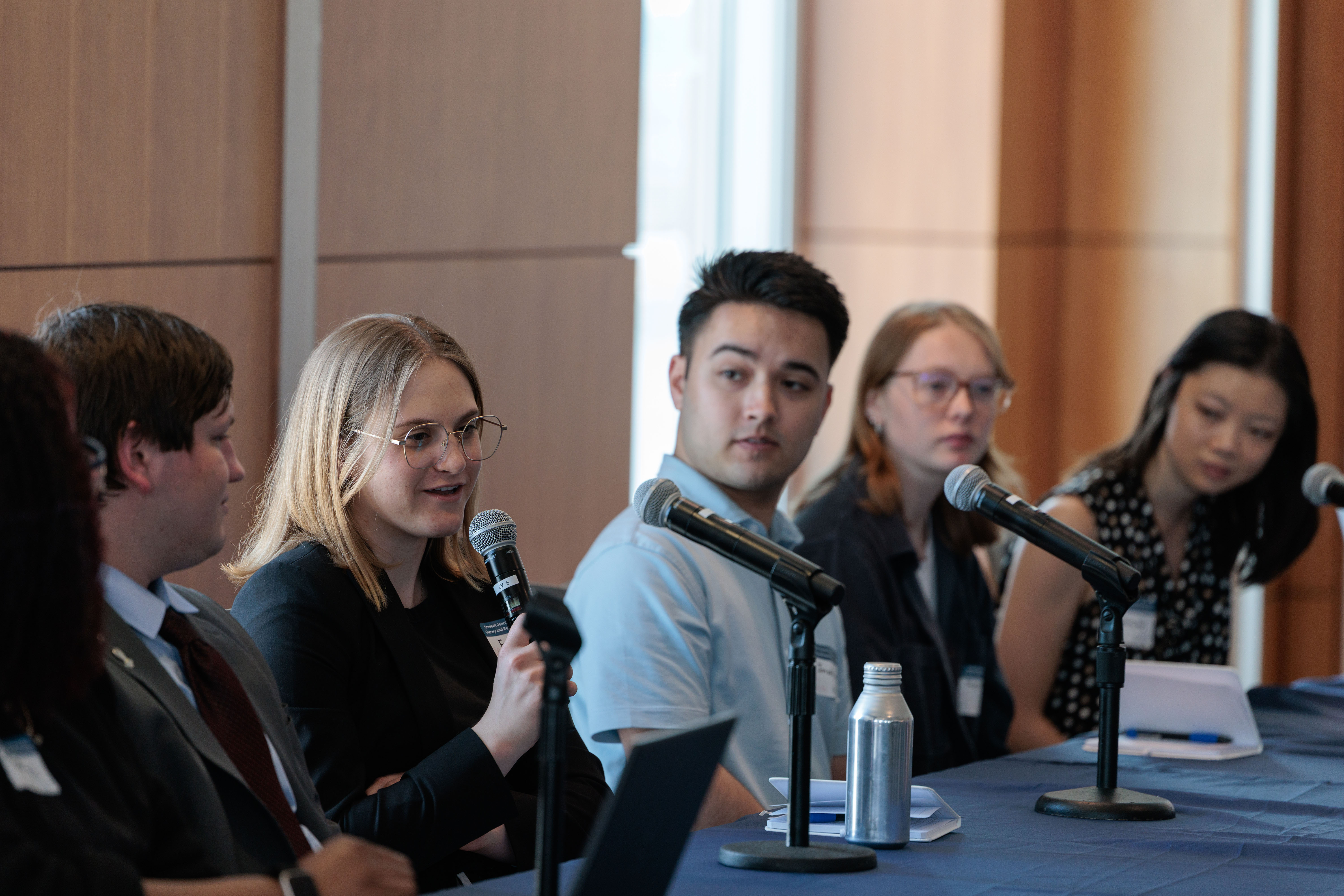students sitting behind table presenting at symposium